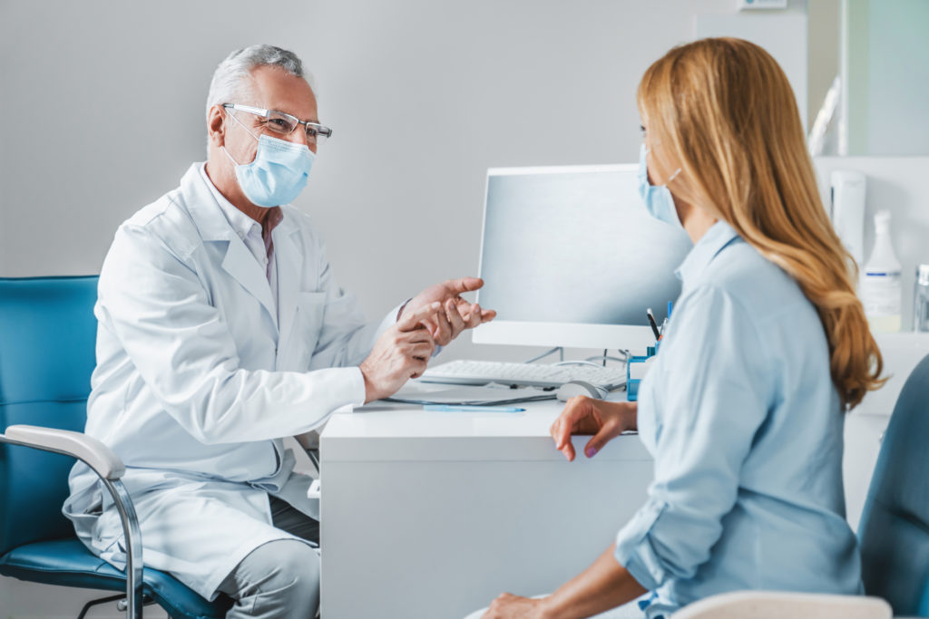 A female businesswoman consults with a mature male doctor to be proactive about their health.