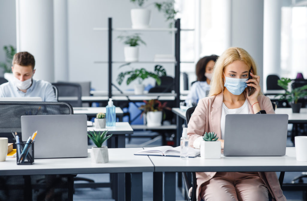  Employees wearing face masks work in the office being proactive with their health by social distancing. 