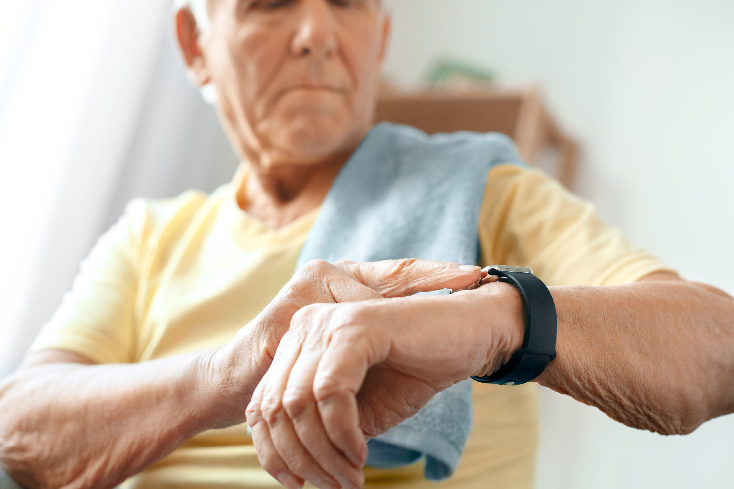 Senior man uses an at-home healthcare pulse measuring device. 