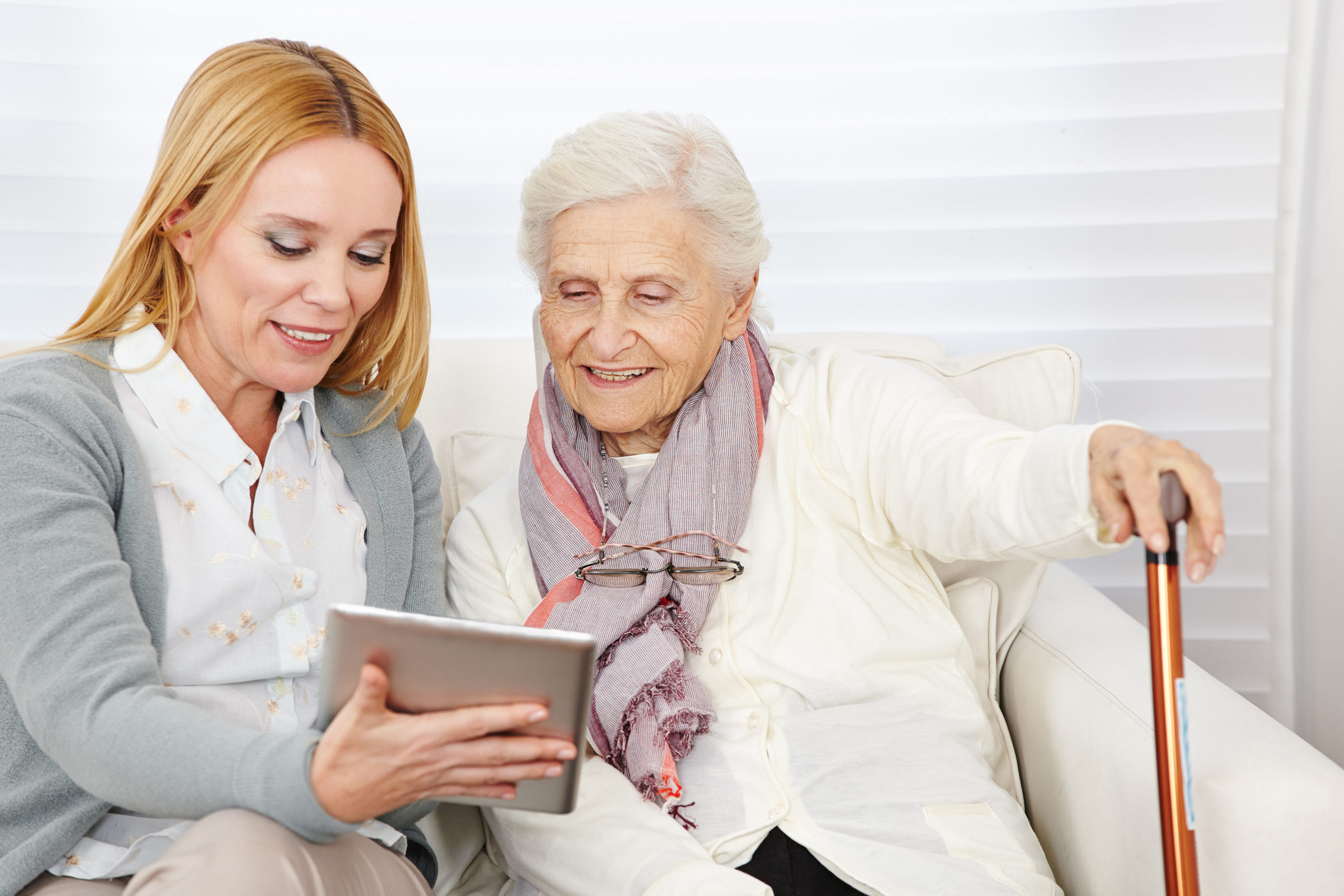 Woman giving senior woman introduction to the internet with a tablet computer. 