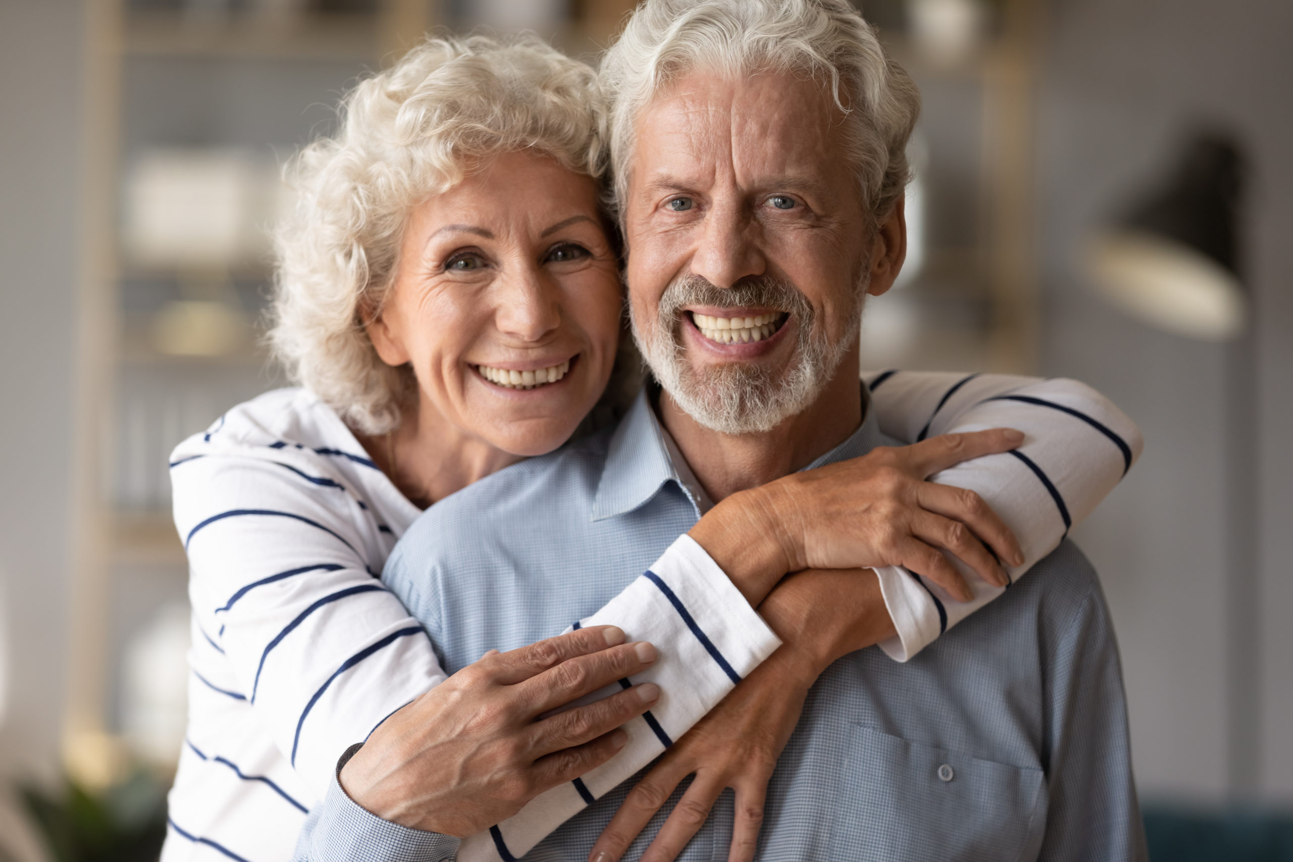 A middle-aged couple smile and embrace.