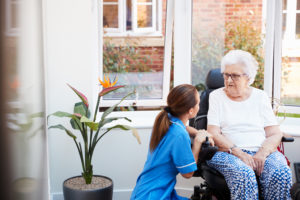 Older woman talks with healthcare provider in an assisted living setting.