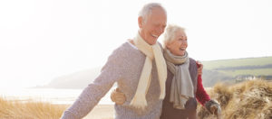A happy older couple strolls through sand dunes together.
