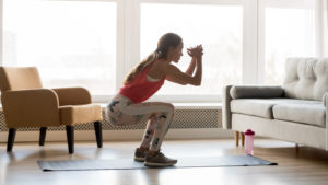 Woman in her living room doing a workout. 