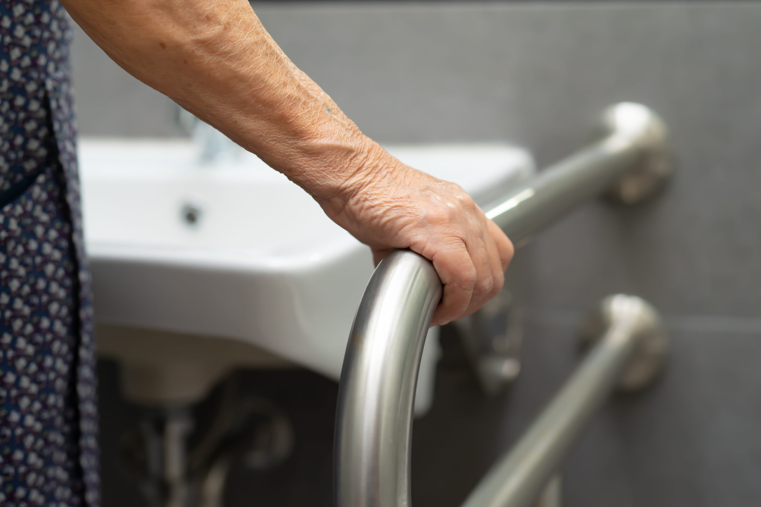 Senior woman holds a grab rail near her sink. 