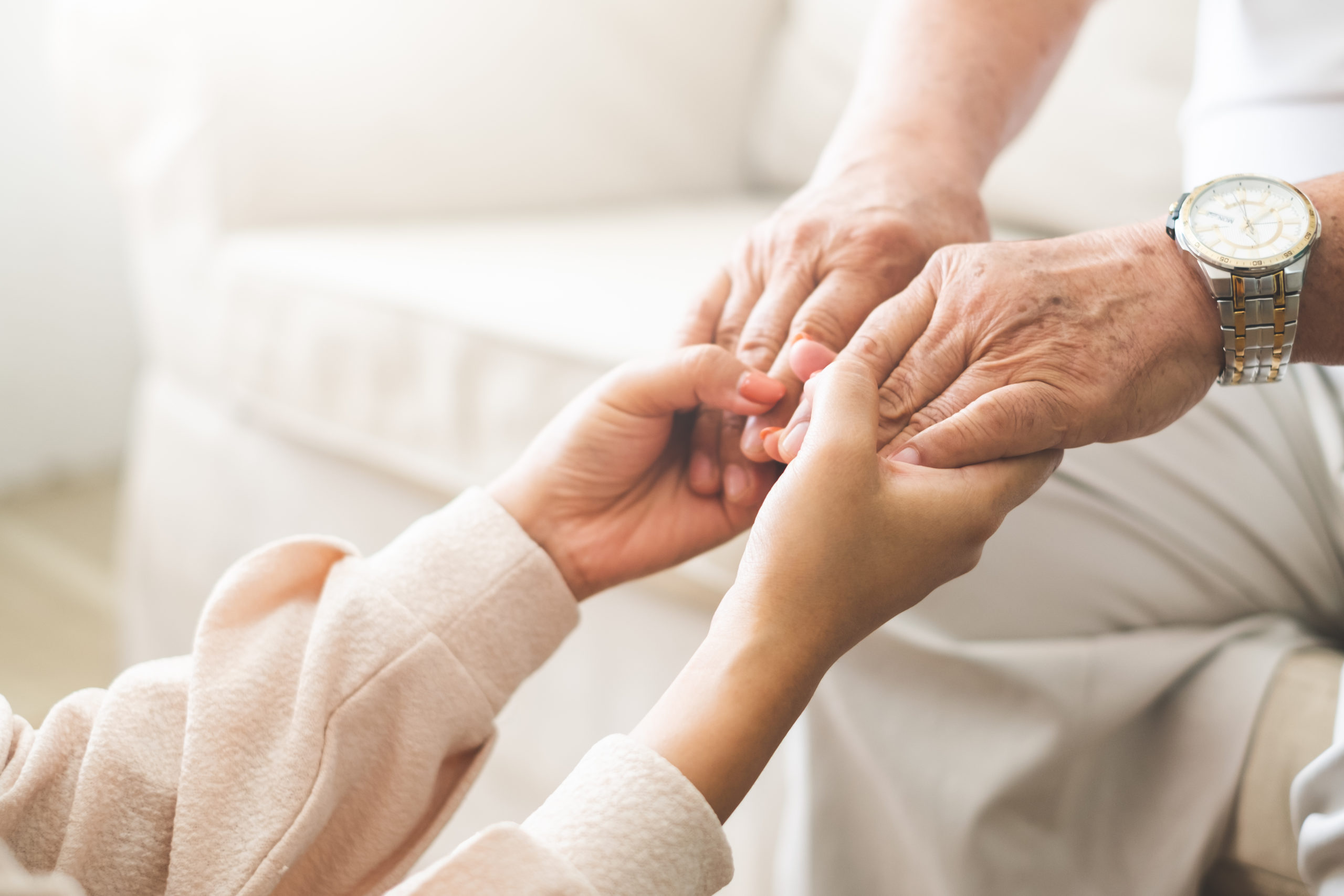 A young woman holds the hands of an older relative, showing care and support. 