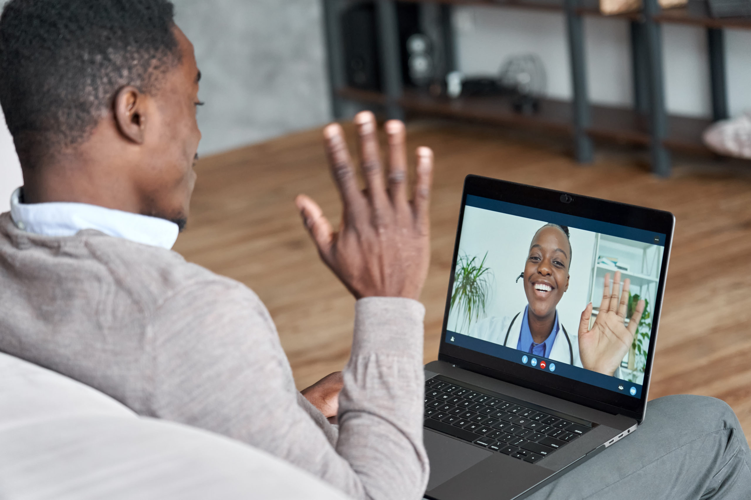 A male patient waves to his doctor during a telehealth video conference.