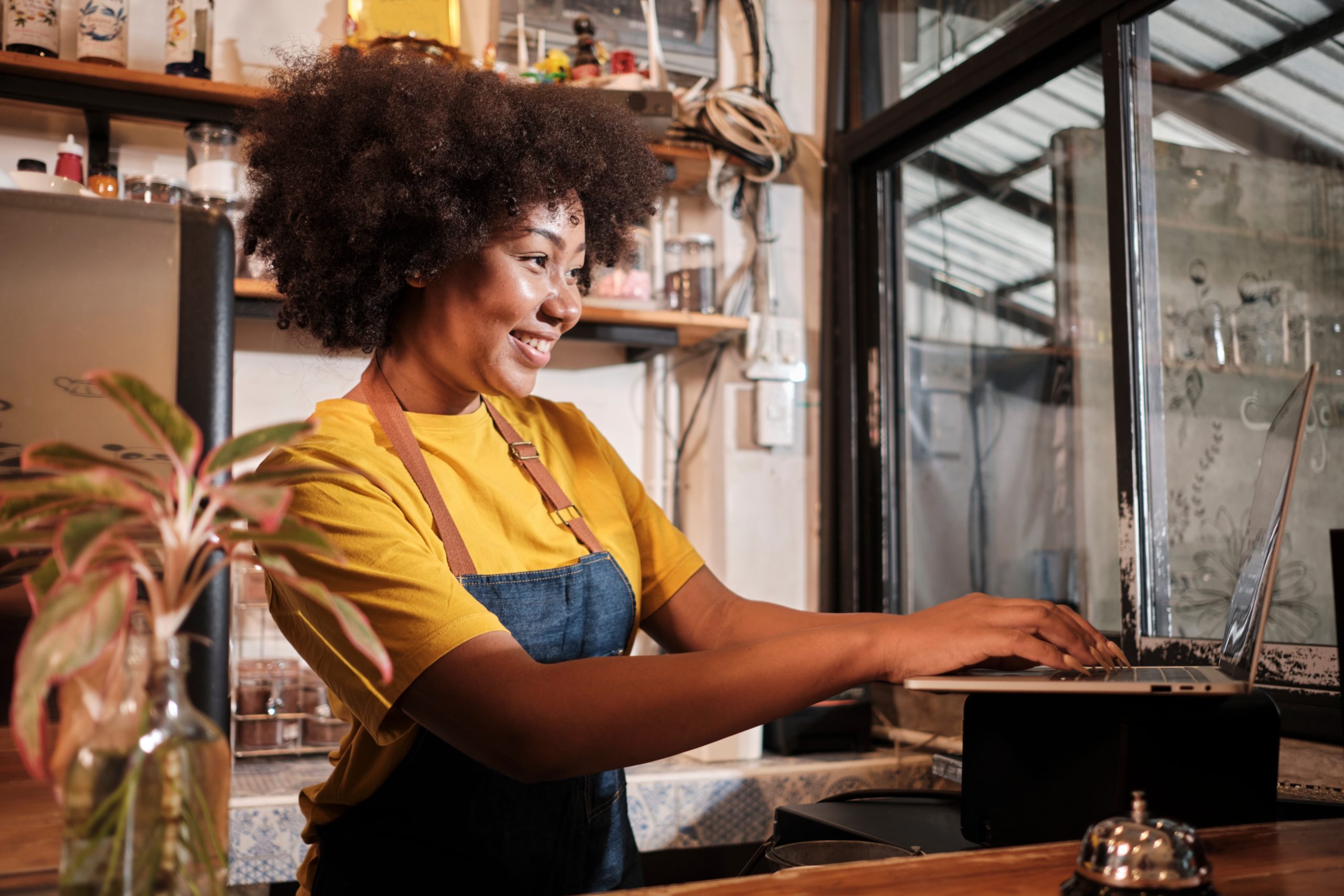  A smiling female cafe worker uses a computer at work. 
