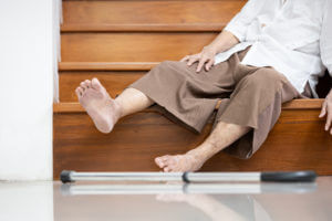 Senior woman sitting on the stairs after a fall.