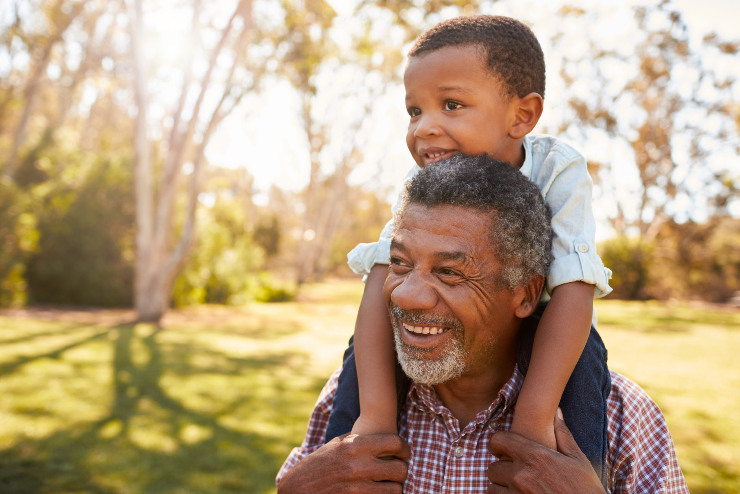 A grandpa gives his grandson a piggyback ride, knowing he can enjoy their time together because of medical alert smartwatches. 