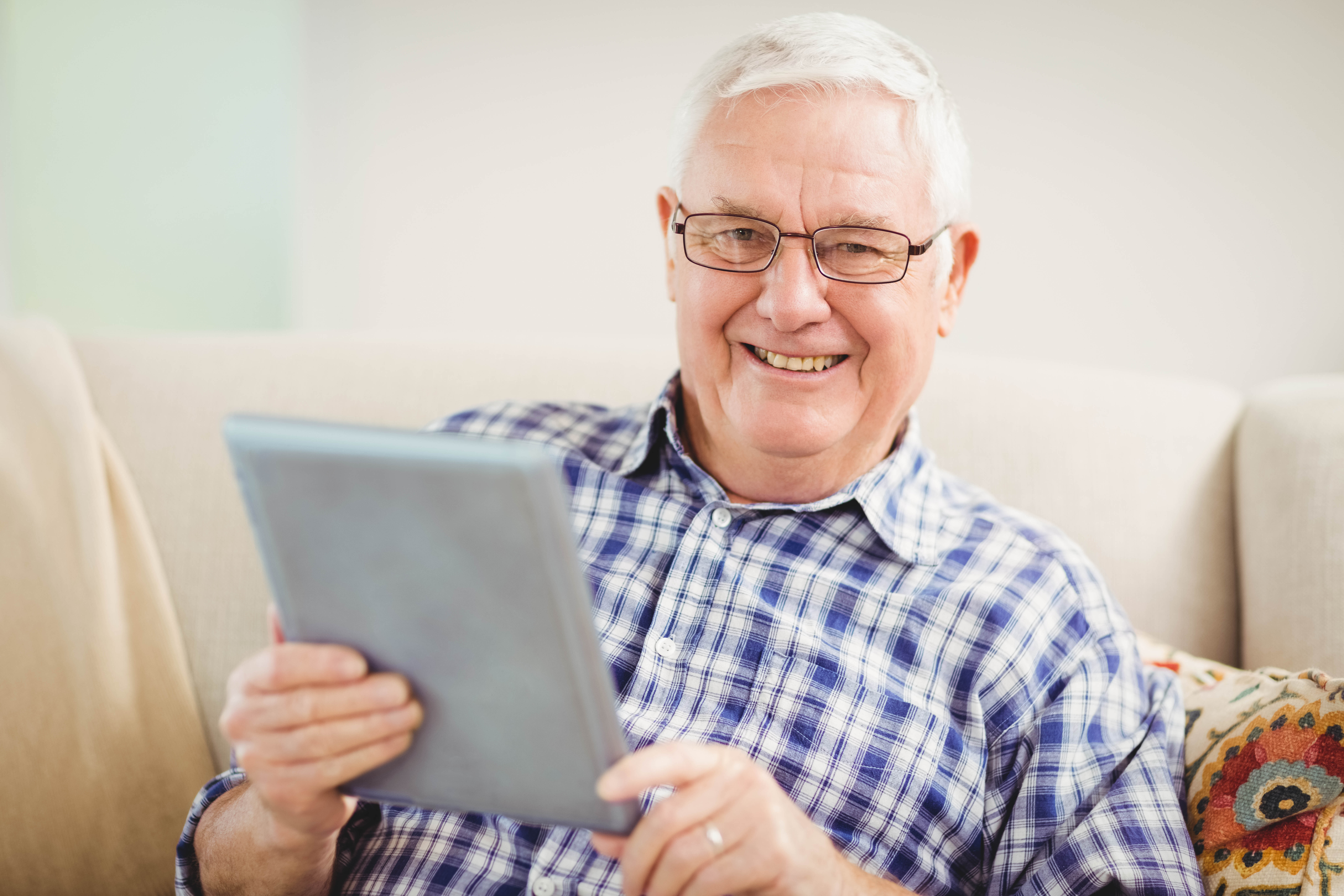 Senior man smiling and using a tablet.
