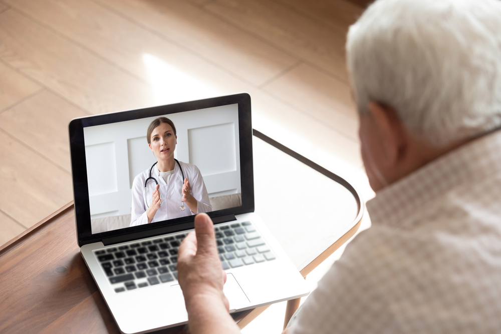 Senior on a laptop during a telehealth session with his doctor. 
