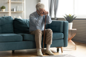 An older gentleman rests his head on his hands as he is one of the millions dealing with elderly depression.
