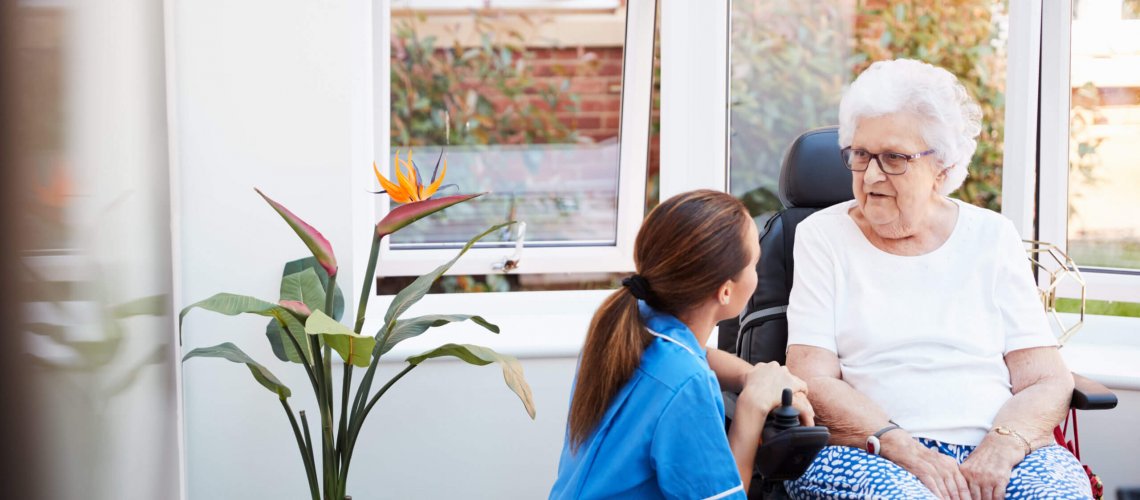 Older woman talks with healthcare provider in an assisted living setting.