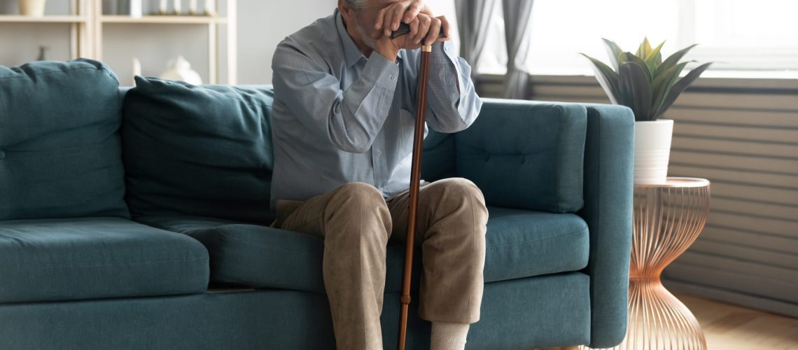 An older gentleman rests his head on his hands as he is one of the millions dealing with elderly depression.
