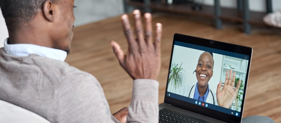 A male patient waves to his doctor during a telehealth video conference.