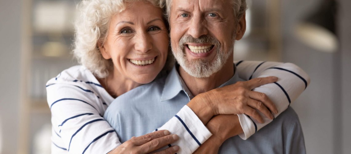 A middle-aged couple smile and embrace.