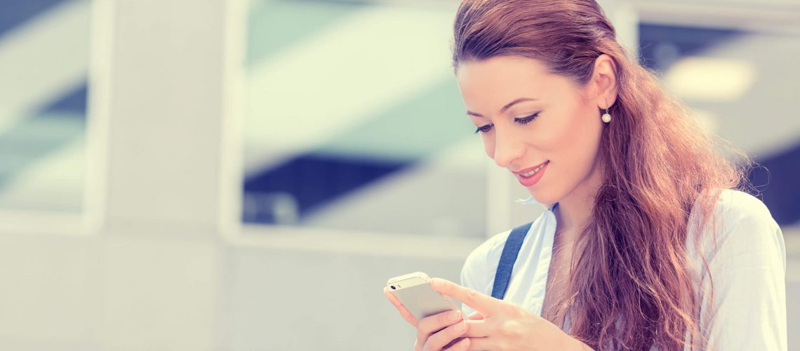 A young businesswoman is happy looking at her phone while in transit viewing her employee benefits.